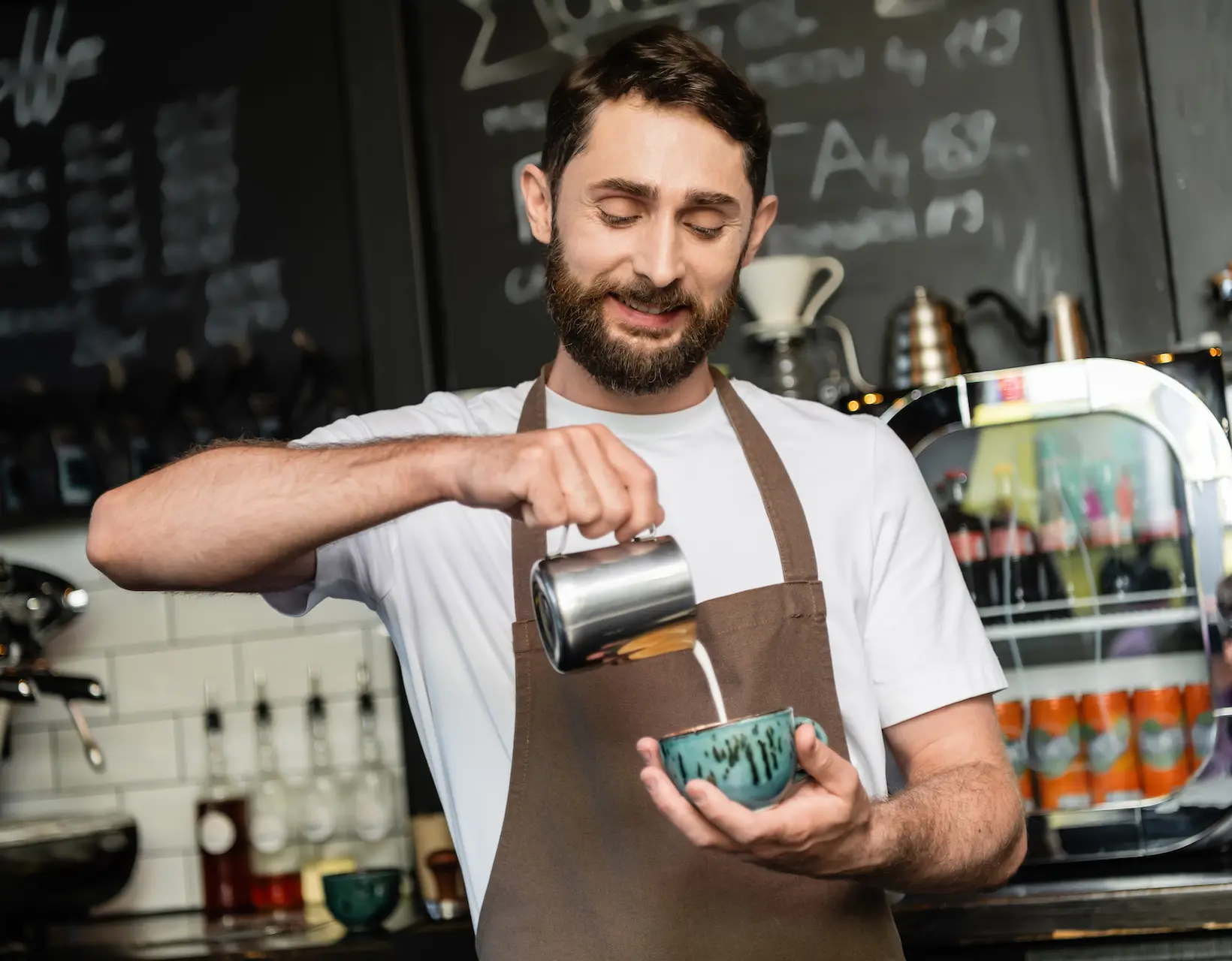 Barista care toarnă lapte într-o ceașcă